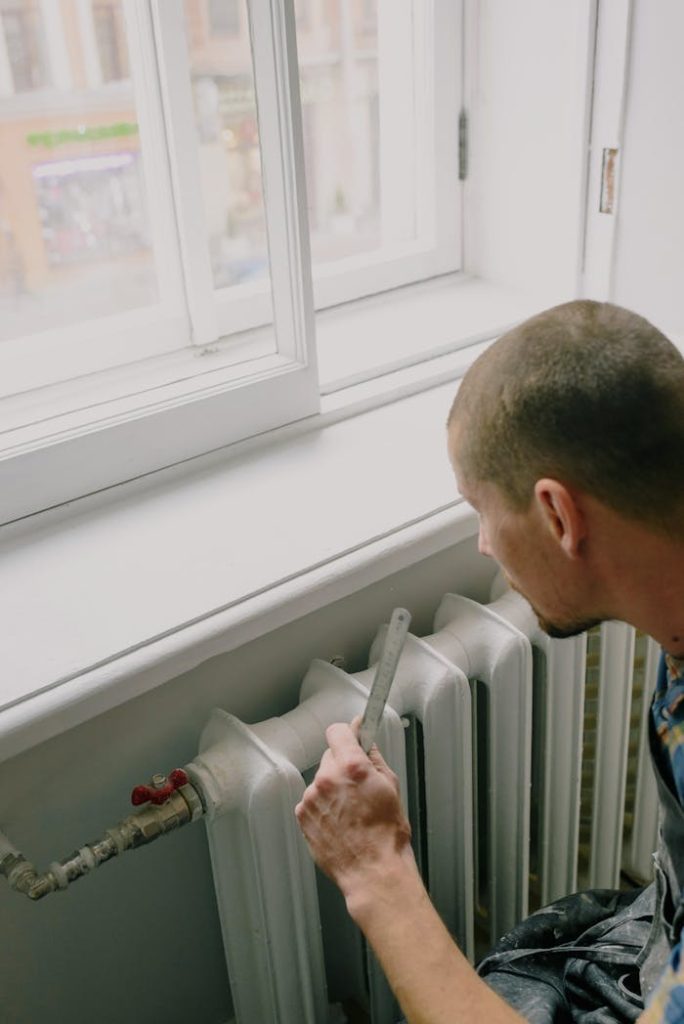 pexels-photo-5691536 From above side view of crop anonymous male worker with ruler near radiator and windowsill in house